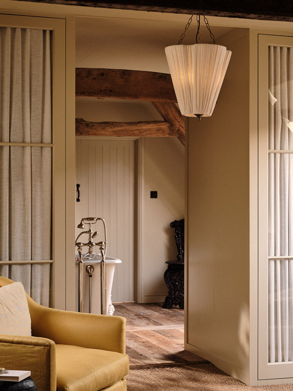 Living room with yellow armchair, wooden beams, and a chandelier.