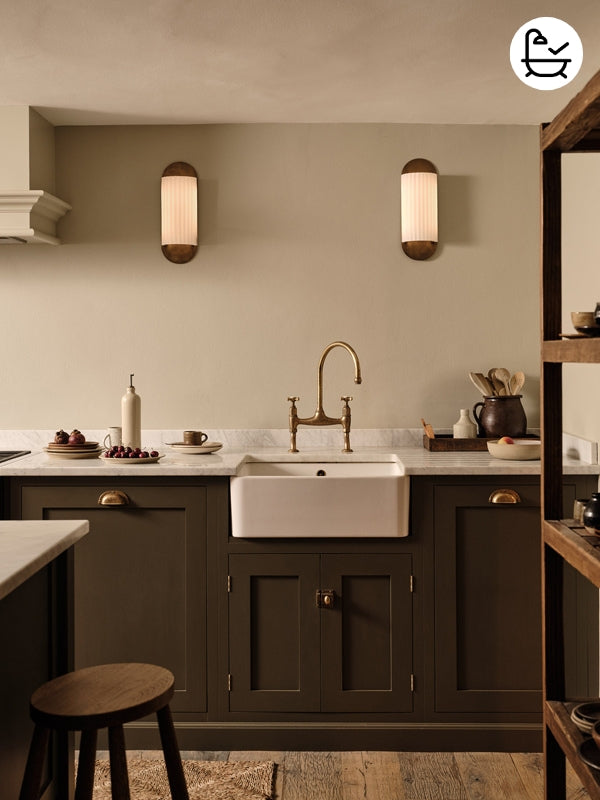 Wall-mounted mirror with aged brass base and top on a beige background in kitchen