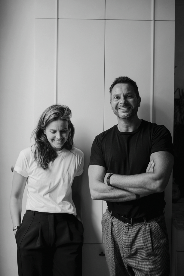 Two people standing against a plain wall, black and white photo