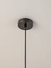  dark metal canopy and cord, suspended against a plain white wall and ceiling.