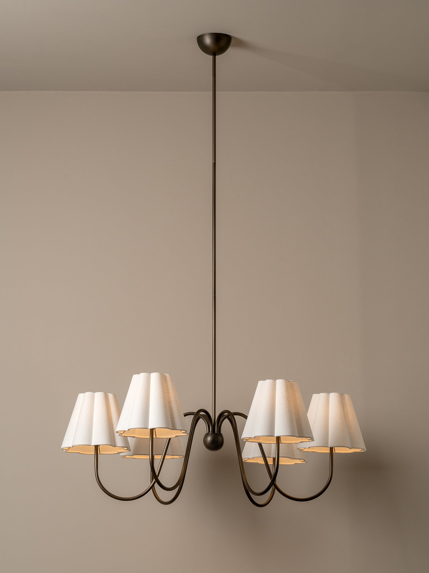 Chandelier with white lampshades on a beige wall