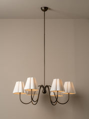 Chandelier with white lampshades on a beige wall