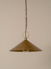 A brass pendant light with a wide conical shade, hanging from a chain against a plain beige background.