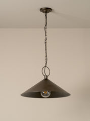 A dark bronze metal pendant light with a wide conical shade hanging from a chain against a plain beige wall.