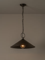 A dark metal pendant light with a wide conical shade hanging from a chain and ceiling canopy against a plain beige wall.