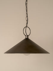 A dark metal cone-shaped pendant light hanging from a chain and ring against a plain beige background.