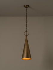 A single hanging pendant light with a tapered metal shade in a warm brass or bronze finish, suspended from a chain against a plain neutral wall.