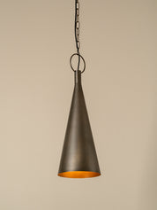 A single cone-shaped pendant light in a dark bronze finish with a warm orange-gold interior, hanging from a chain against a plain beige background.
