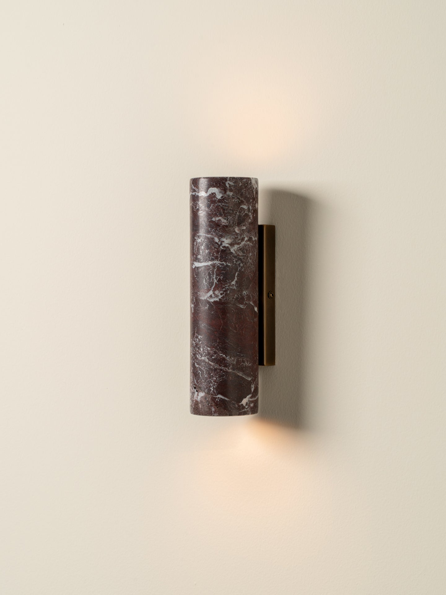 Wall-mounted cylindrical light fixture with a textured surface on a beige wall.
