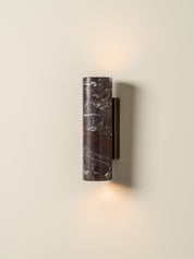 Wall-mounted cylindrical light fixture with a textured surface on a beige wall.