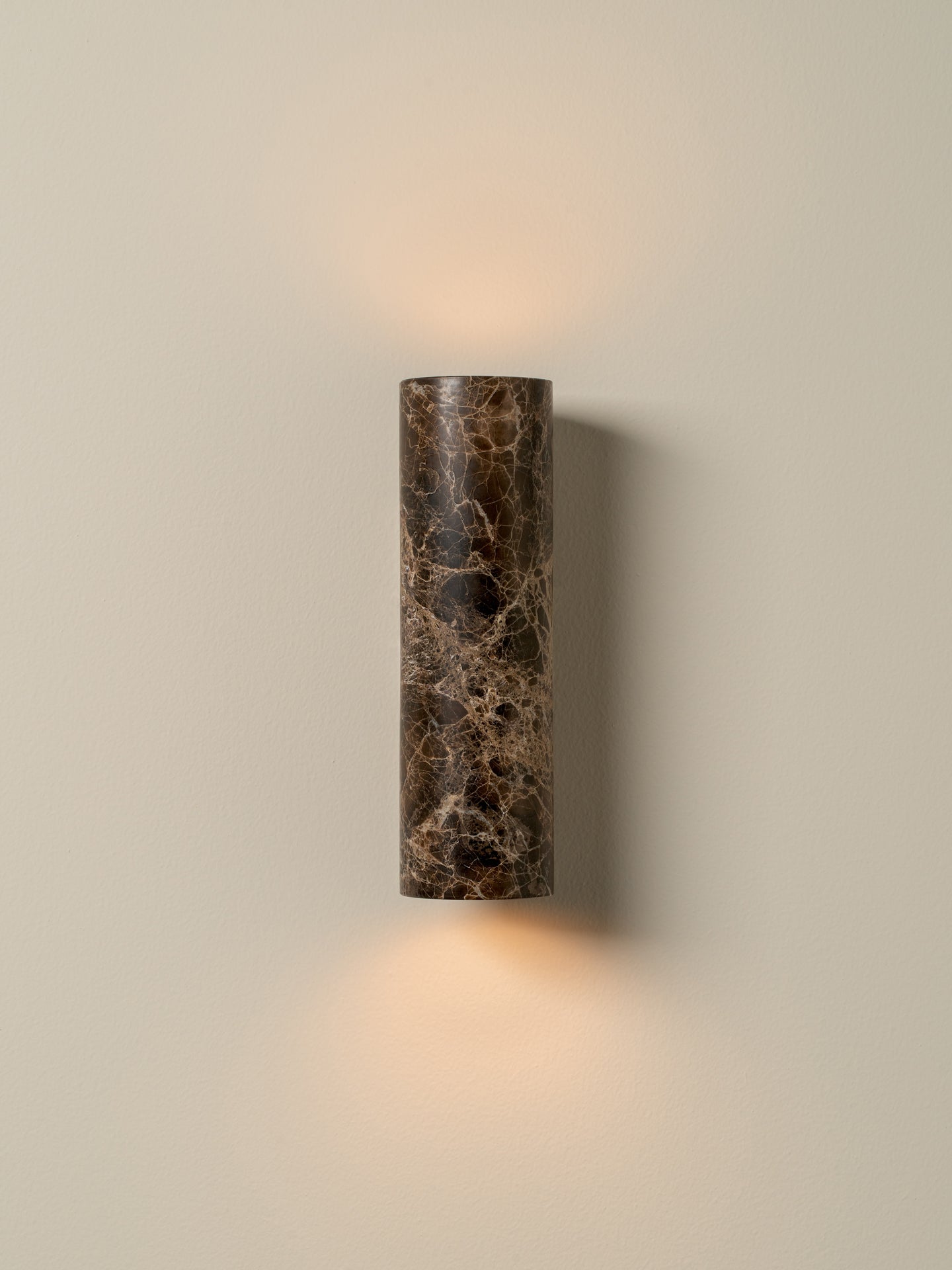 Cylindrical wall sconce with a textured surface on a beige wall.