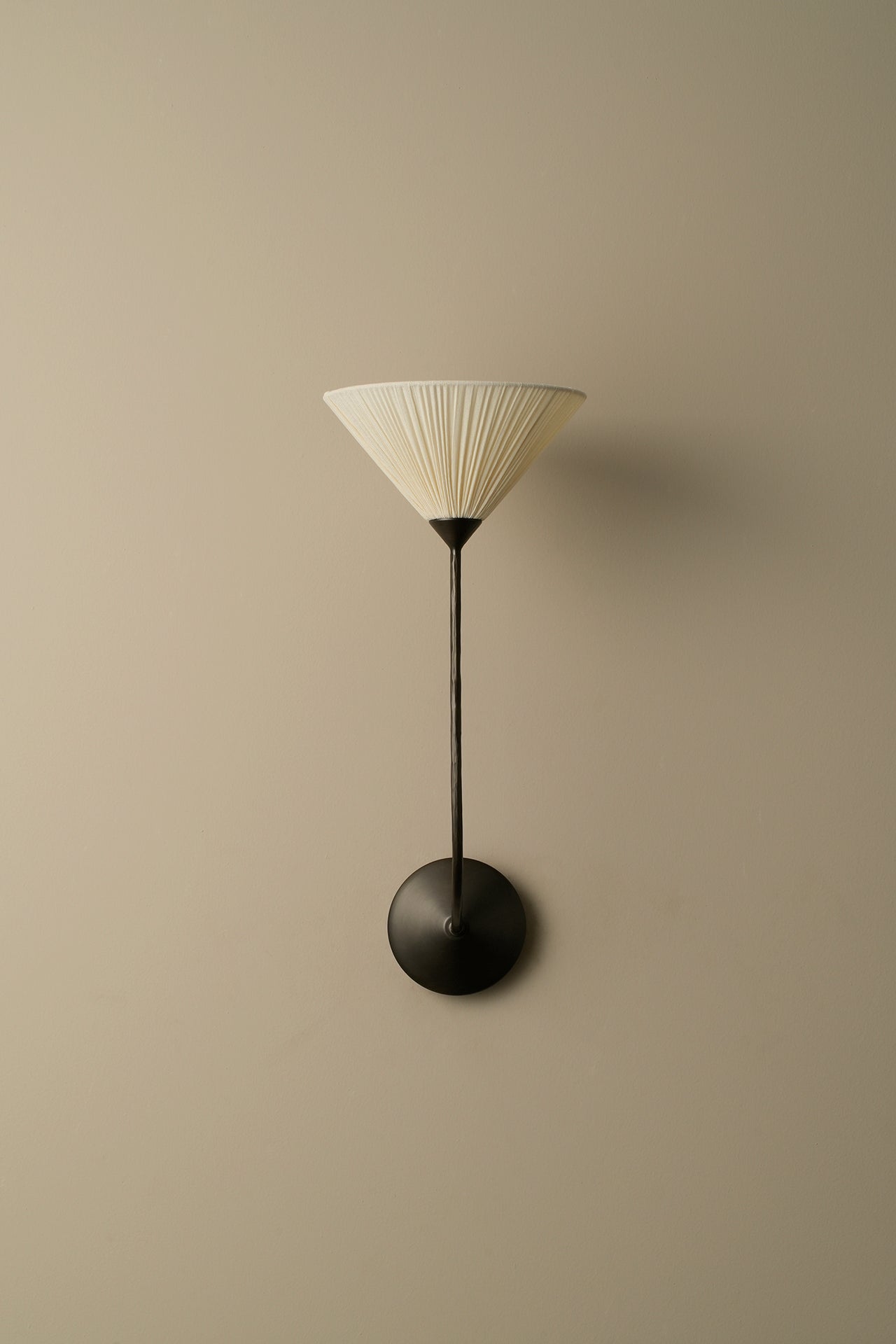 Wall-mounted lamp with a ribbed shade on a beige wall