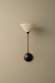 Wall-mounted lamp with a ribbed shade on a beige wall