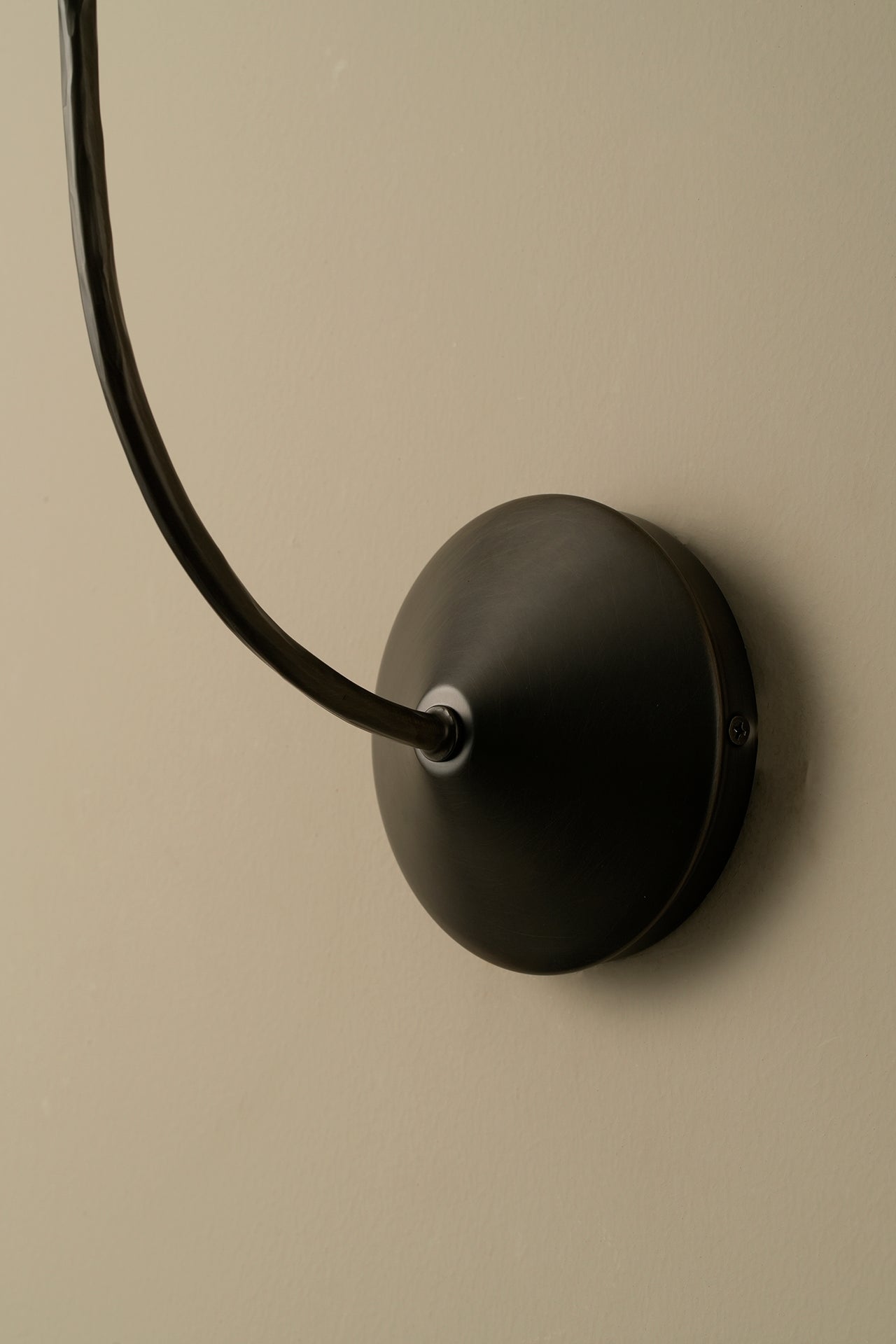 Black wall-mounted lamp with a long black cord on a beige wall.