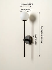 A wall-mounted light fixture with a white spherical globe and a slim black stem and circular backplate, shown against a plain light beige wall with dimension callouts around it.