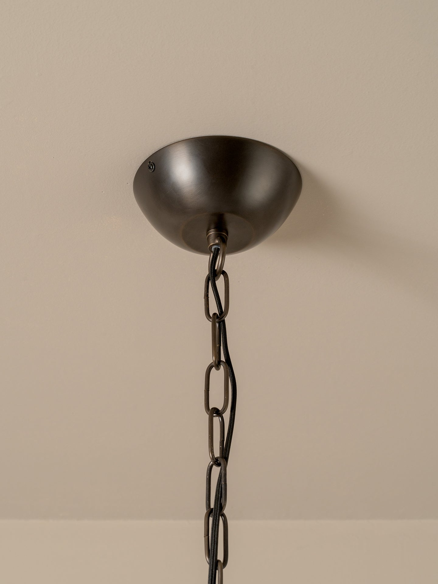 A dark bronze ceiling canopy with a matching chain, shown against a plain beige wall.