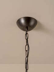 A dark bronze ceiling canopy with a matching chain, shown against a plain beige wall.