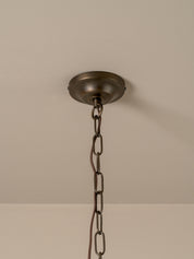 An industrial-style ceiling light fixture with a round, dark bronze ceiling canopy and a matching metal hanging chain, shown against a plain beige wall and ceiling.
