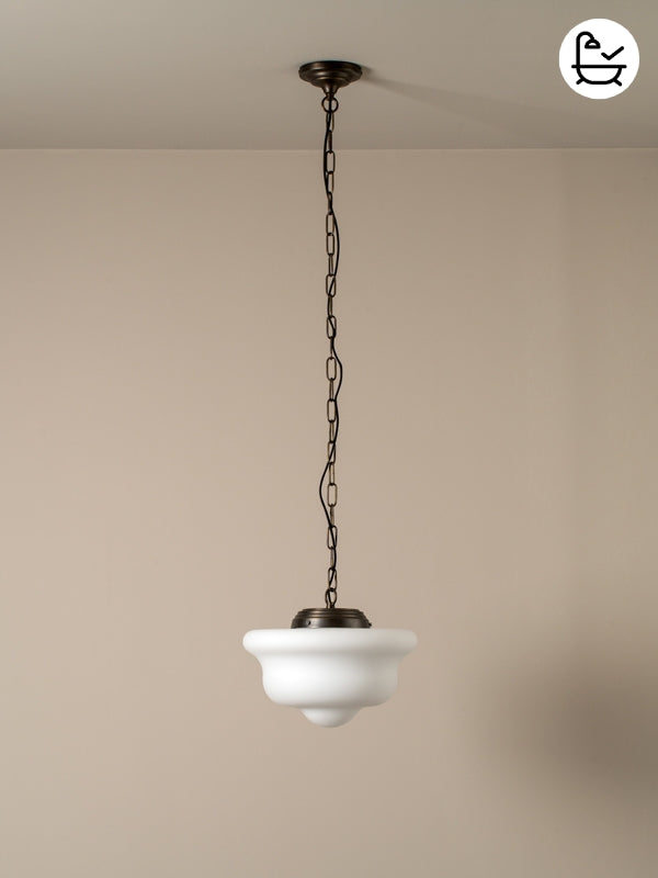 Small pendant light with white glass shade and black chain against a beige wall with bath logo
