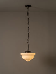 A hanging pendant light with a frosted warm-white glass shade and dark metal chain and canopy, shown against a plain taupe wall and ceiling.