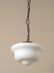 A vintage-style pendant light with a wide, flared white glass shade and a dark metal chain, shown against a solid beige background.