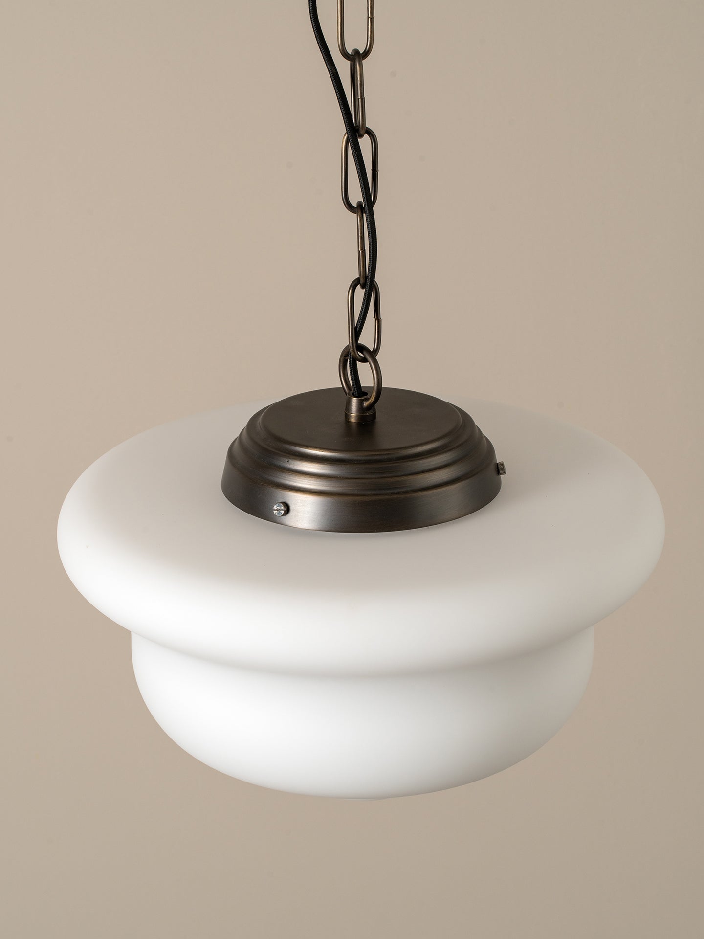 A modern pendant light with a wide, tiered white glass shade and a dark bronze metal canopy and chain, shown against a solid beige background.
