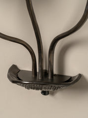 Decorative metal wall hook with a textured finish on a beige background