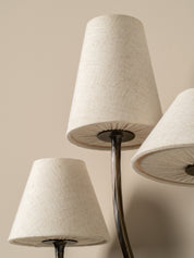 Close-up of a lamp with three beige lampshades on a neutral background