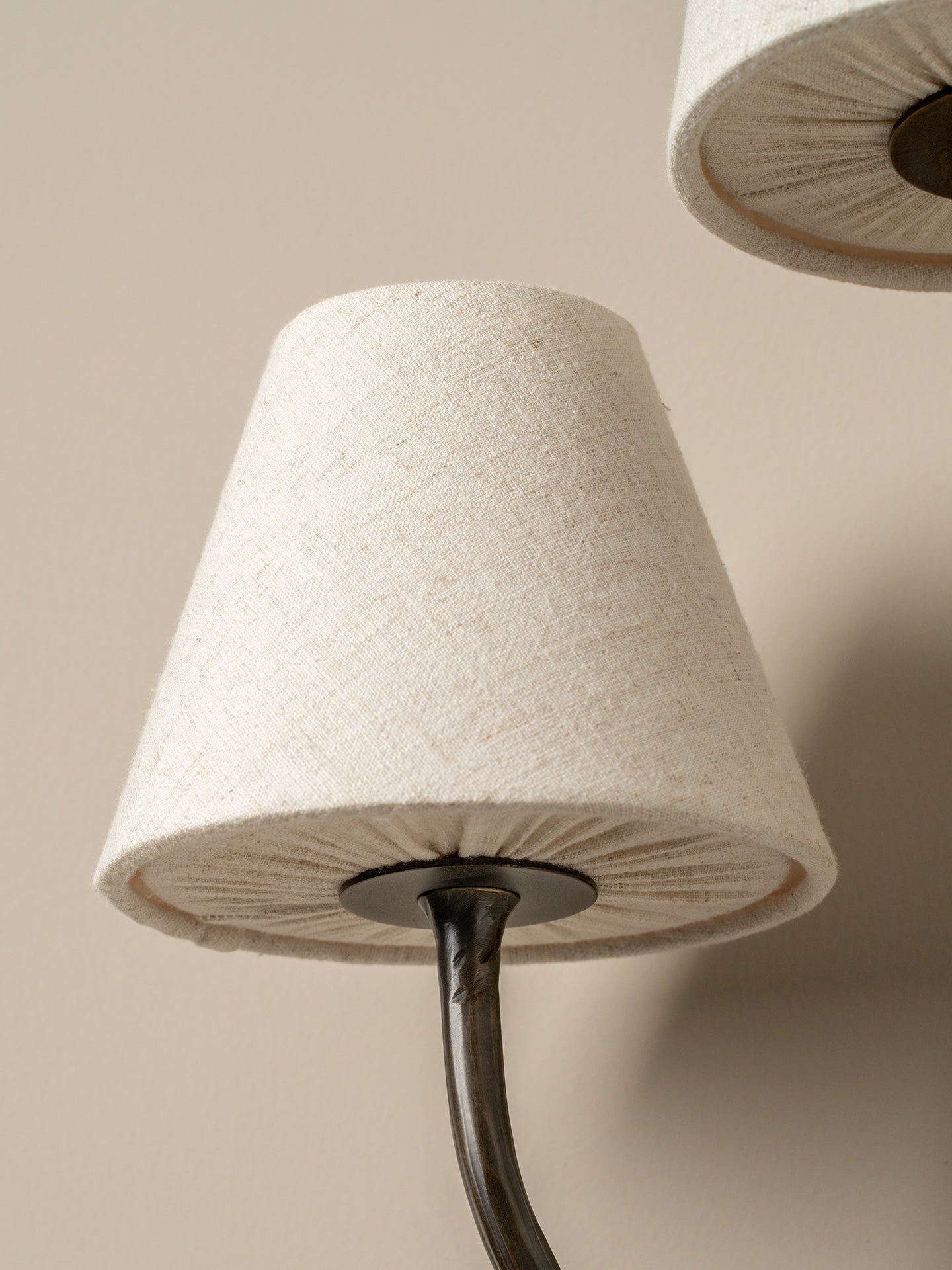 Close-up of a lamp with a textured white shade and dark metal base against a beige background