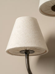 Close-up of a lamp with a textured white shade and dark metal base against a beige background