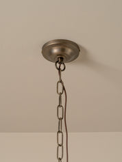 An industrial-style ceiling light fixture canopy with a hanging chain, shown against a plain beige wall and ceiling.
