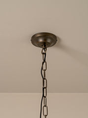 An industrial-style ceiling light fixture with a dark bronze metal ceiling canopy and chain hanging from a beige ceiling.