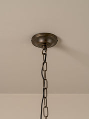 An industrial-style ceiling light fixture with a round, dark bronze ceiling canopy and a matching metal chain suspending the fixture against a plain beige wall and ceiling.