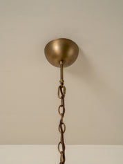 An antique brass ceiling light fixture canopy with a hanging chain, shown against a plain off-white wall.