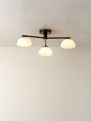 A modern three-light ceiling fixture with a matte black metal frame and frosted white glass shades, shown installed on a plain white ceiling.