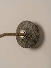 d a round dark green and brown stone backplate, shown against a plain beige wall.