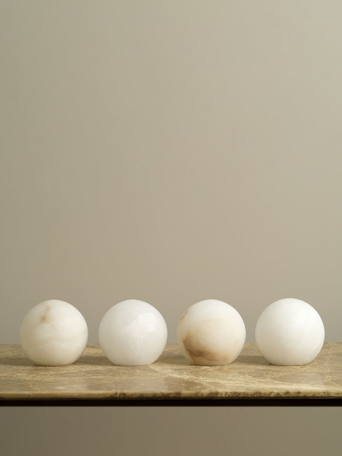 Four marble spheres on a wooden surface with a beige background