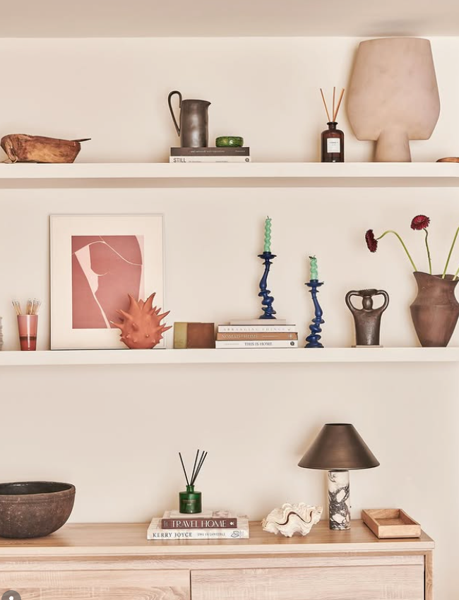Shelves with decorative items including a lamp, books, and vases against a neutral wall.