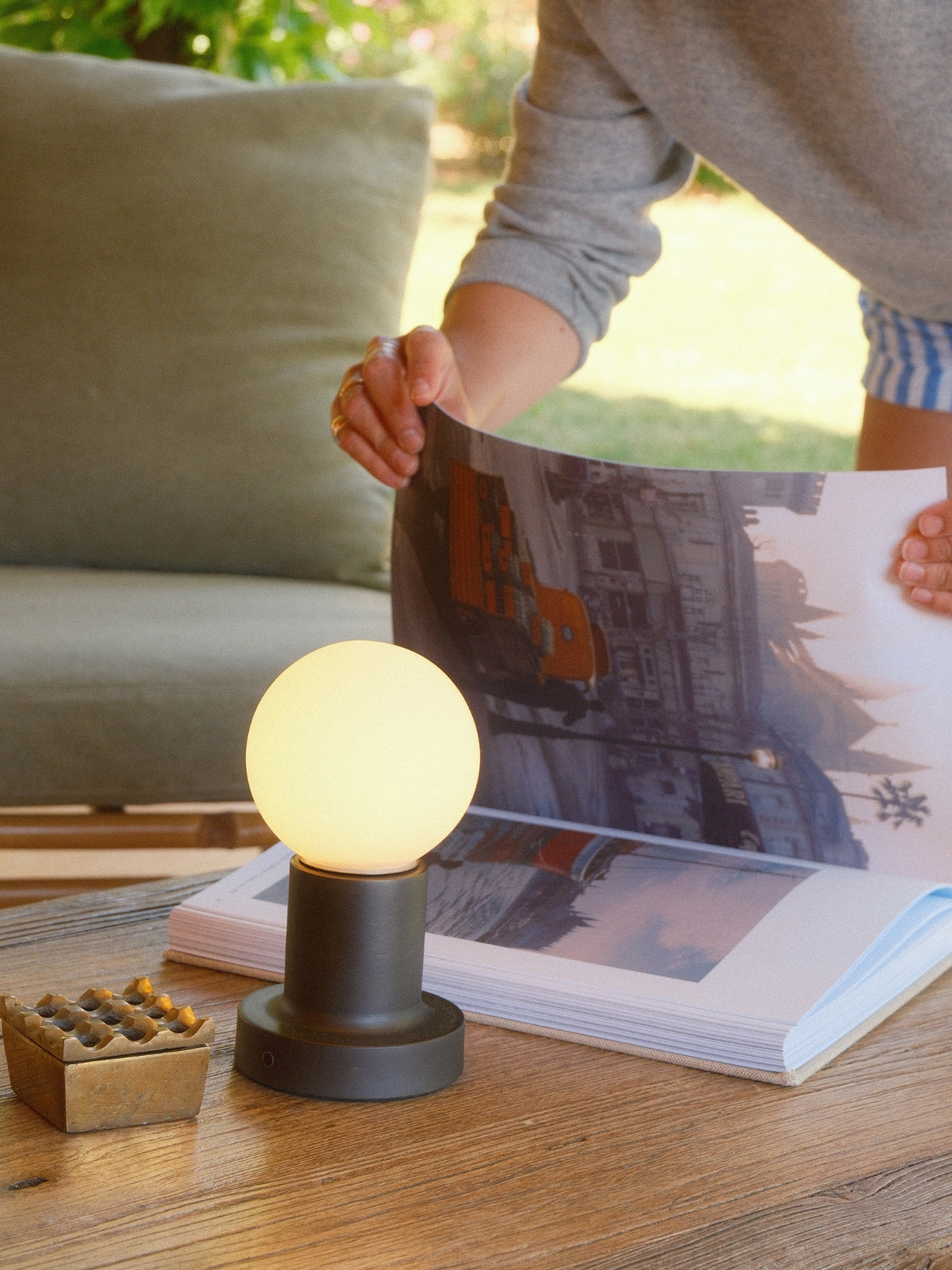 Small lamp on a table with a person holding a magazine in the background